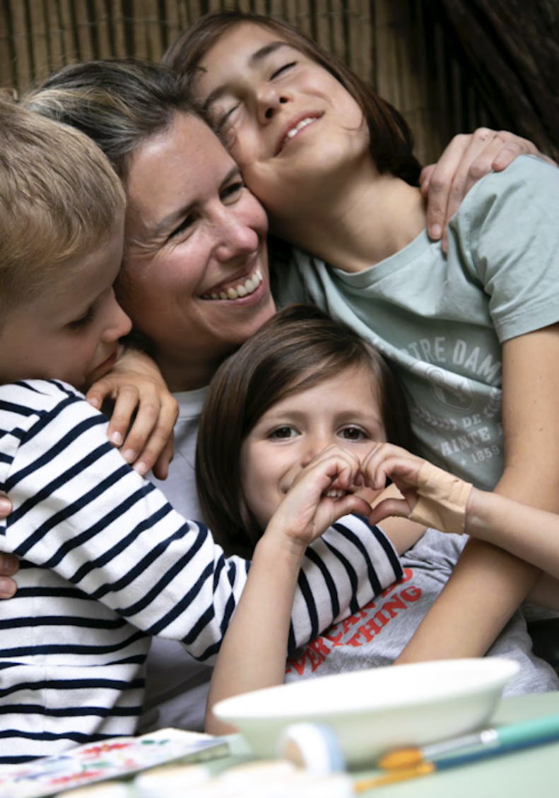 une maman souriante avec ses trois enfants
